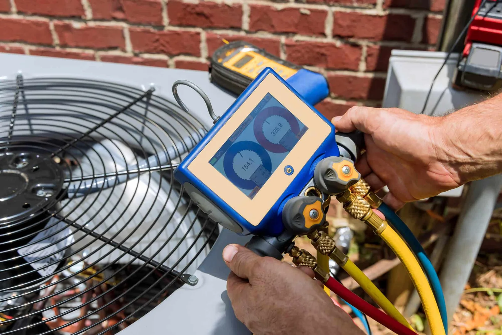 HVAC technician checking condenser pressure with digital gauges